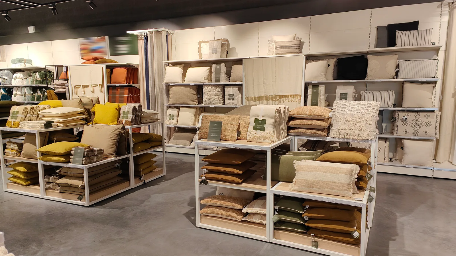 Linéaire de coussins et plaids avec produits pliés, exposés et rangés par familles