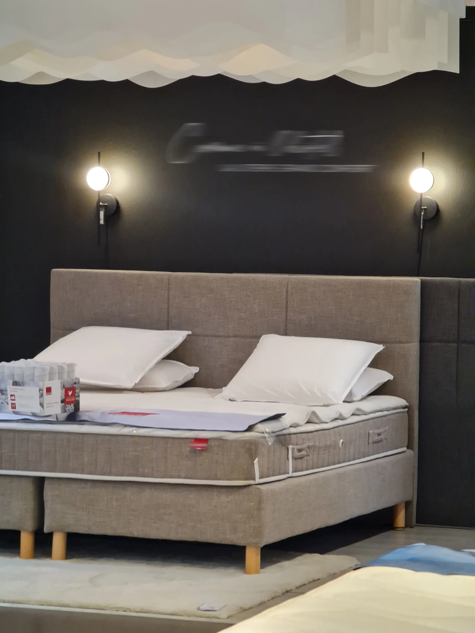 Mise en ambiance d’un lit avec tête de lit, éclairages et fond sombre